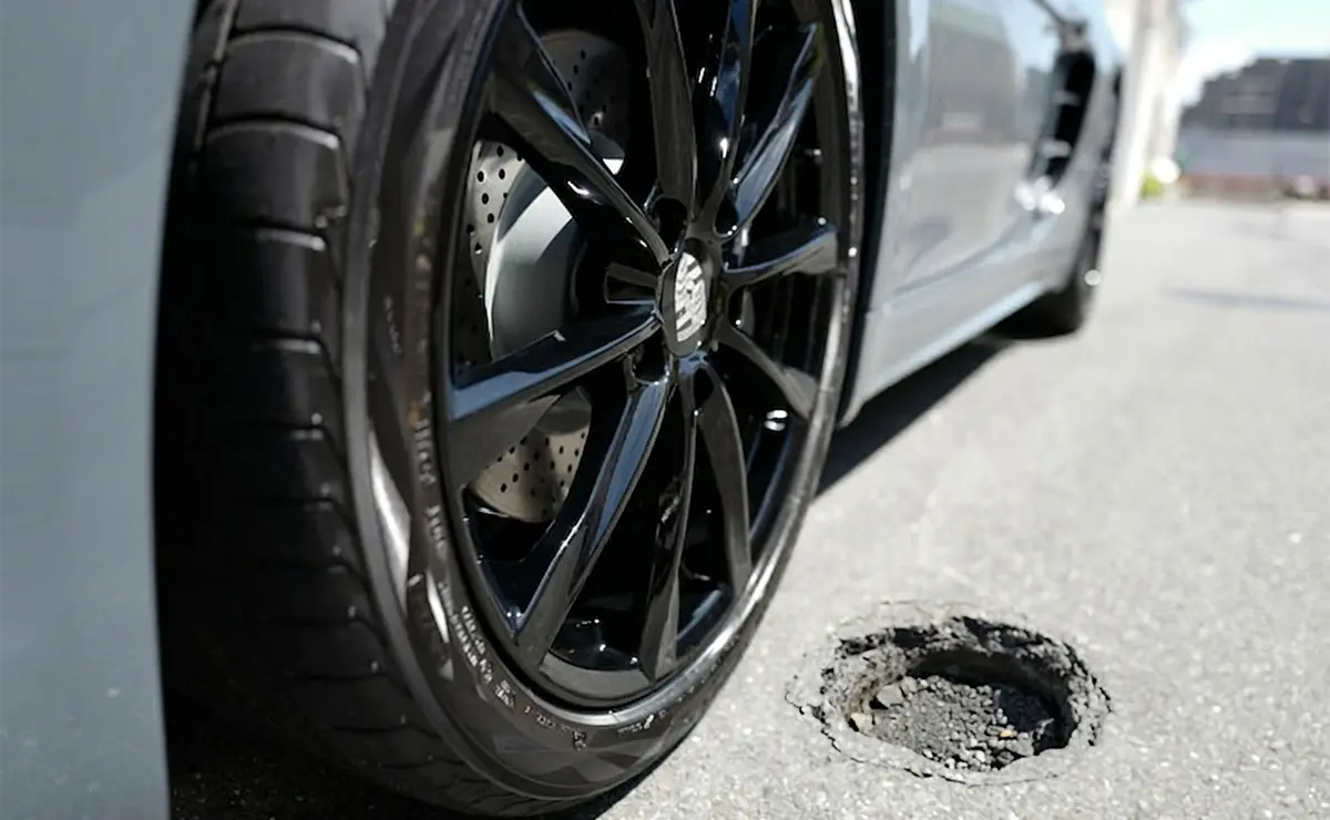 ポルシェ718ケイマンのタイヤ / ホイールと道路上に空いた穴（AI生成）